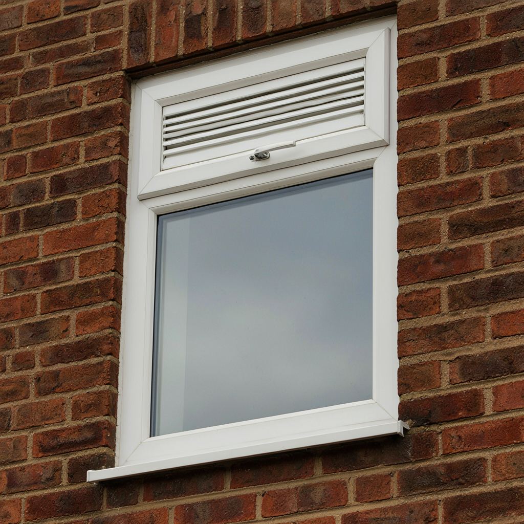 Directe opname van een strak wit kunststof kozijn voorzien van inbraakwerend beslag en een smal ventilatierooster