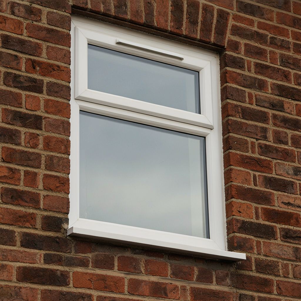 Close-up van een wit kunststof kozijn met ingebouwd ventilatierooster en espagnoletslot