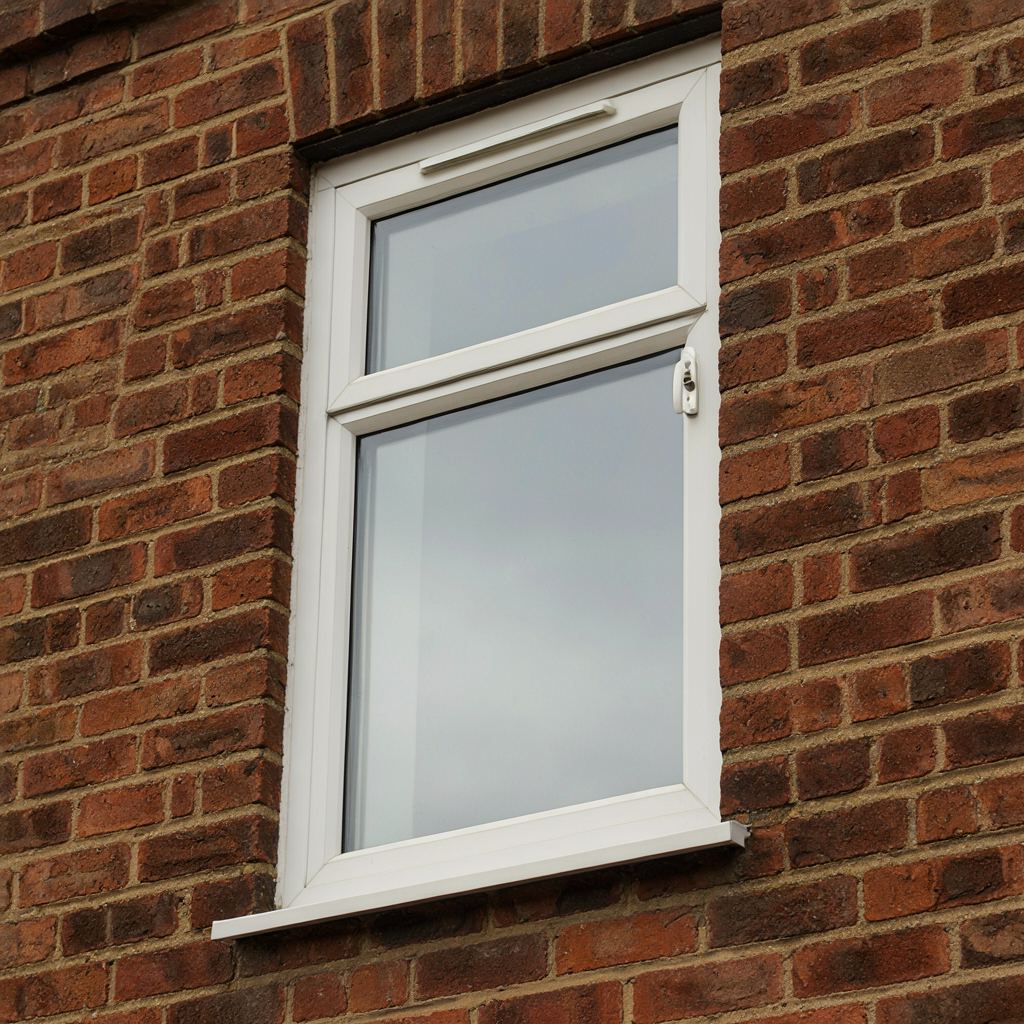 Detailfoto van een wit kunststof kozijn met een geïntegreerd ventilatierooster en hendelslot in 's-Gravendeel
