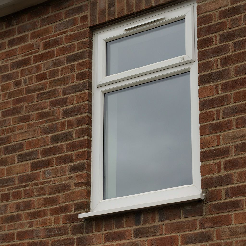 Close-up van een wit kunststof kozijn met ingebouwd ventilatierooster en espagnoletslot