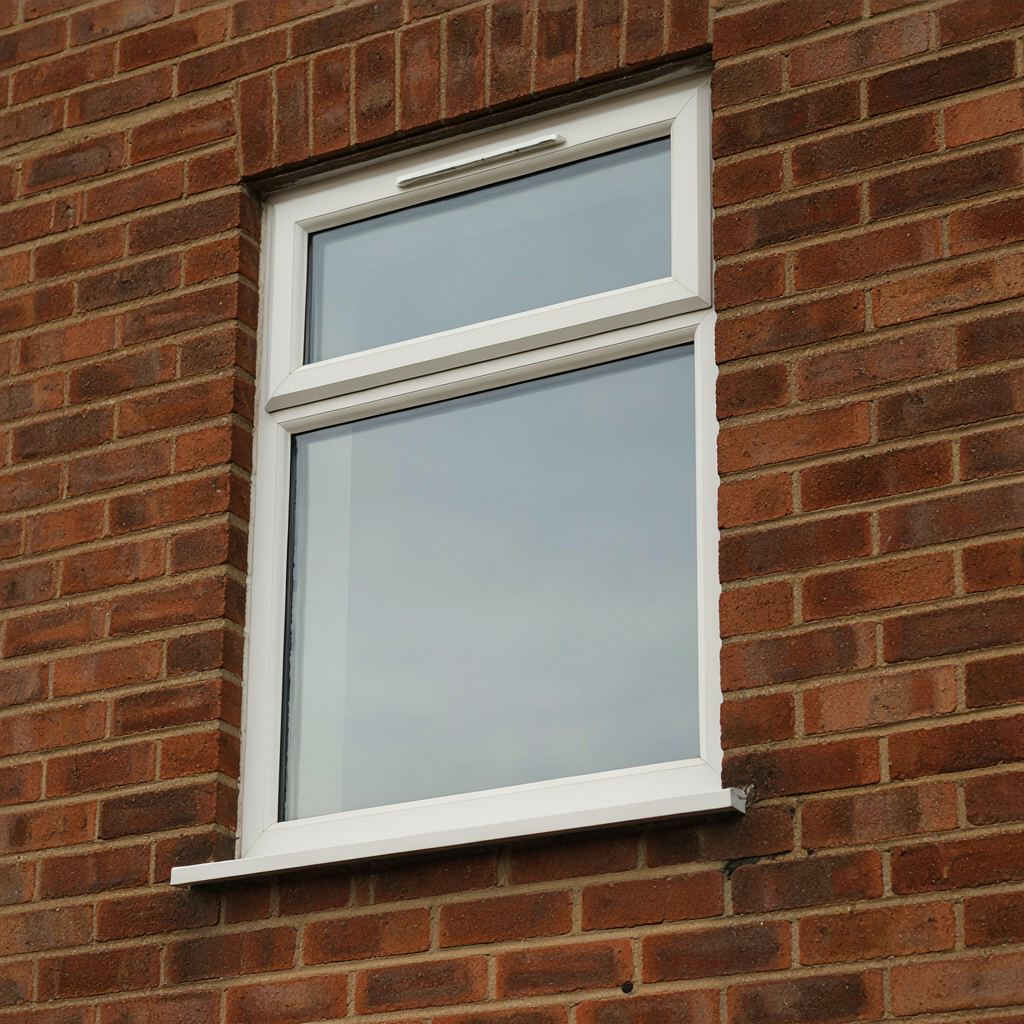 Detailopname van een wit kunststof draai-kiepraam met geïntegreerd ventilatierooster