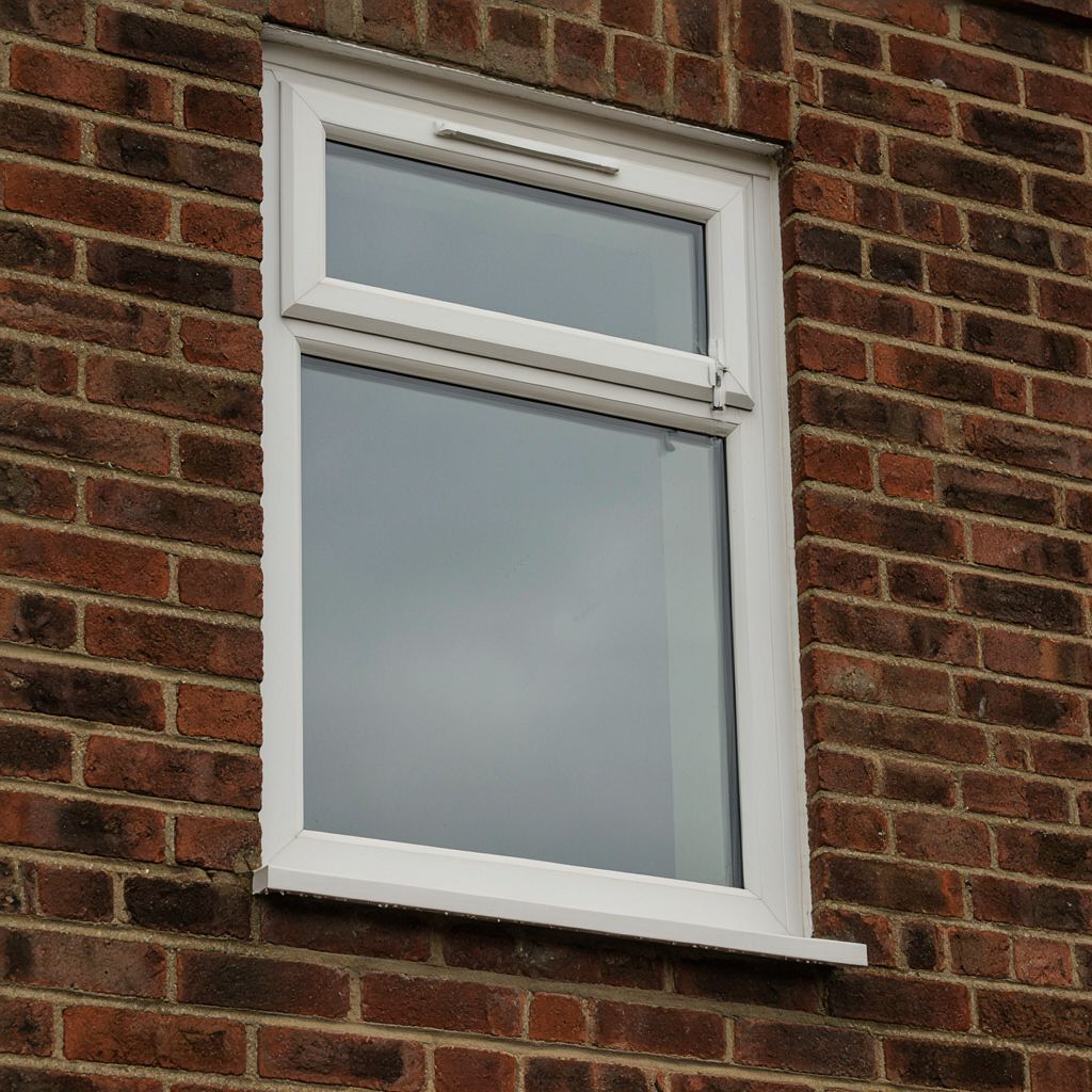 Close-up van een wit kunststof kozijn met ingebouwd ventilatierooster en espagnoletslot